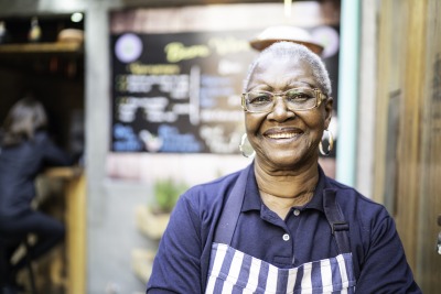 Senior woman working and standing in front of restaurant