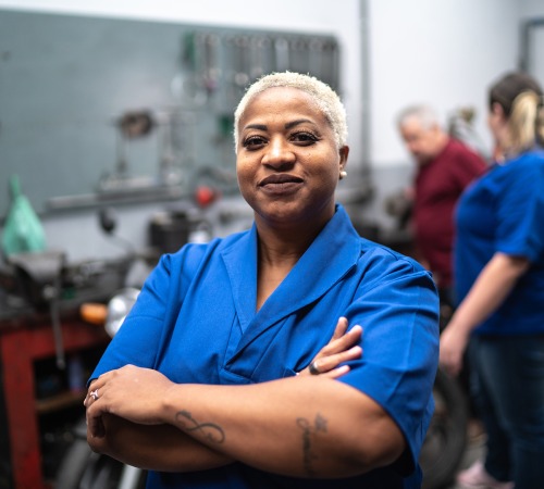 Smiling woman with arms crossed in auto repair